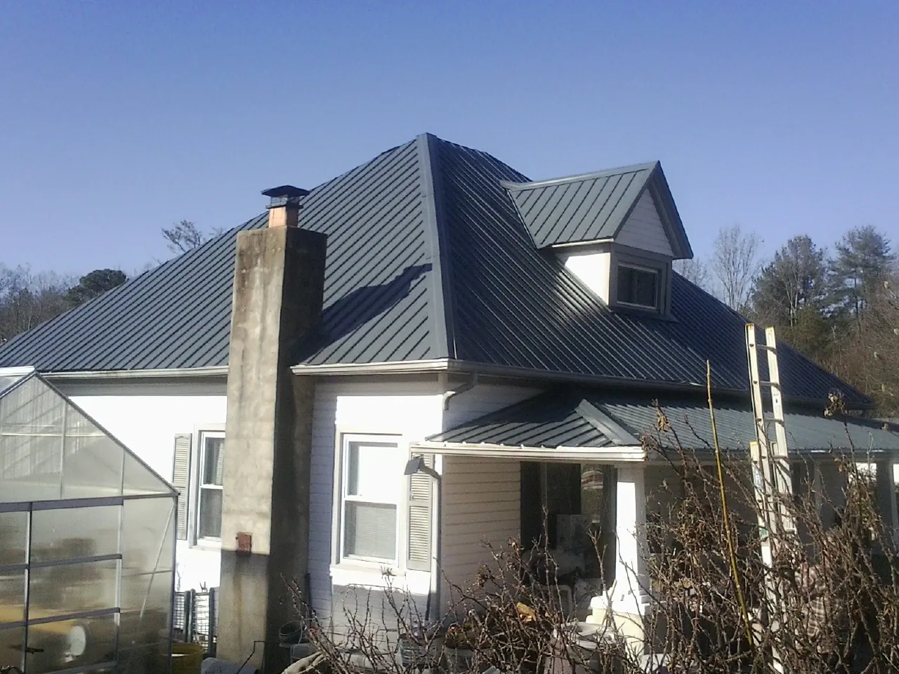 Dark blue standing seam metal roof on a white farmhouse with dormer — Slate & Tile Roof Repair by Roofing Brothers in Glasgow