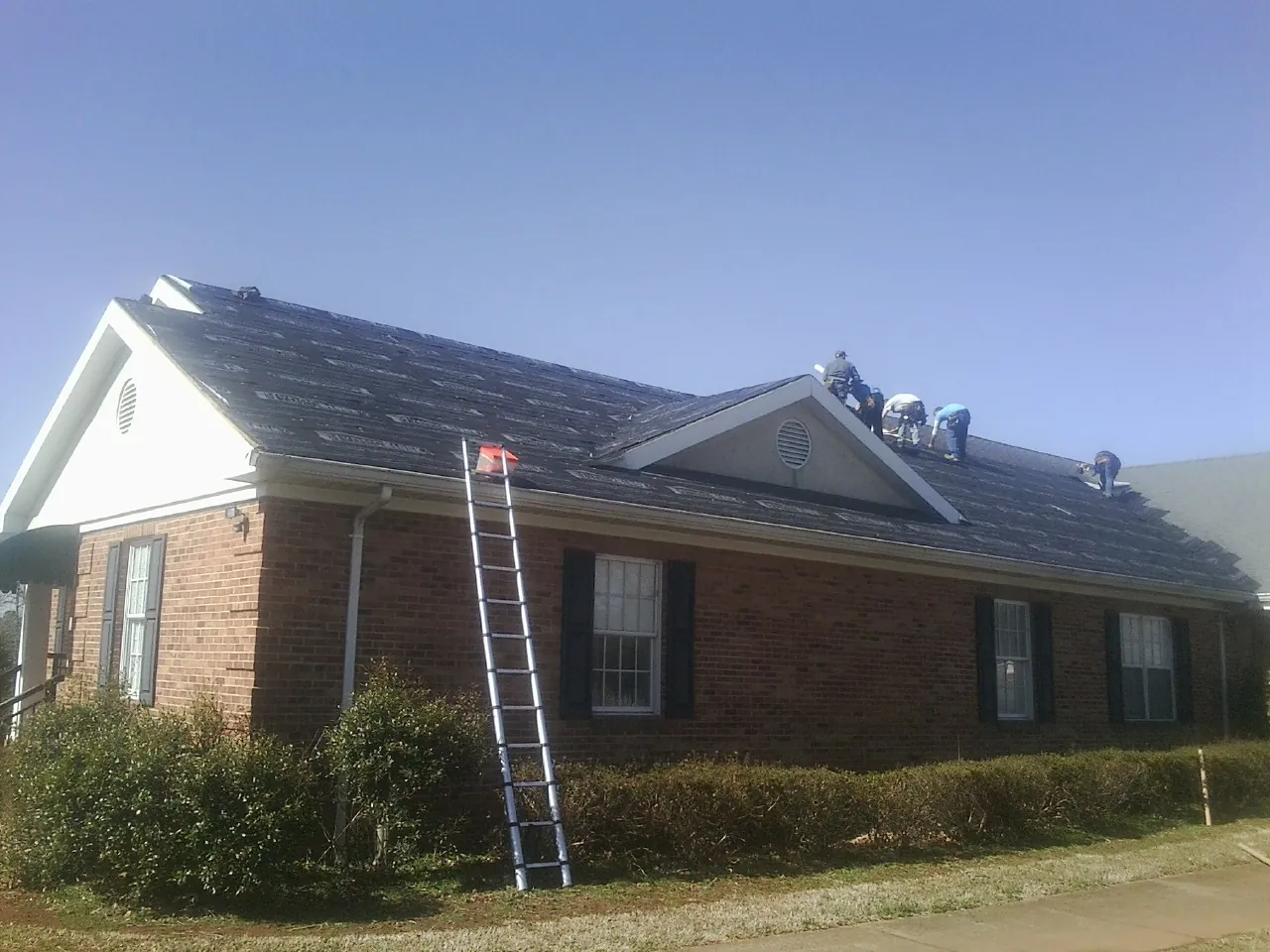 Crew tearing shingles off a brick ranch roof with a ladder set — Metal Roof Repair work by our crew in Glasgow