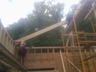 Carpenter raising a rafter beam on a new second story frame in Glasgow