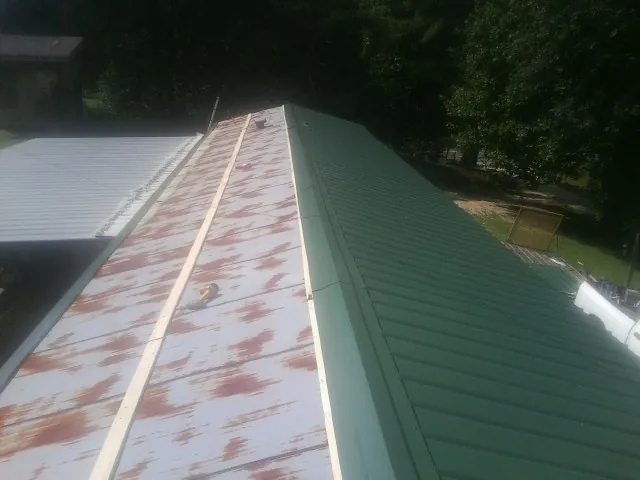 Old rusted panels beside newly installed green metal roofing — Wind Damage Roof Repair by Roofing Brothers in Glasgow