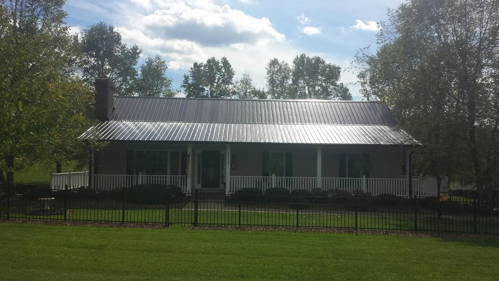 Gray metal roof on a brick ranch with a full width front porch — Gutter Guard Installation work by our crew in Glasgow