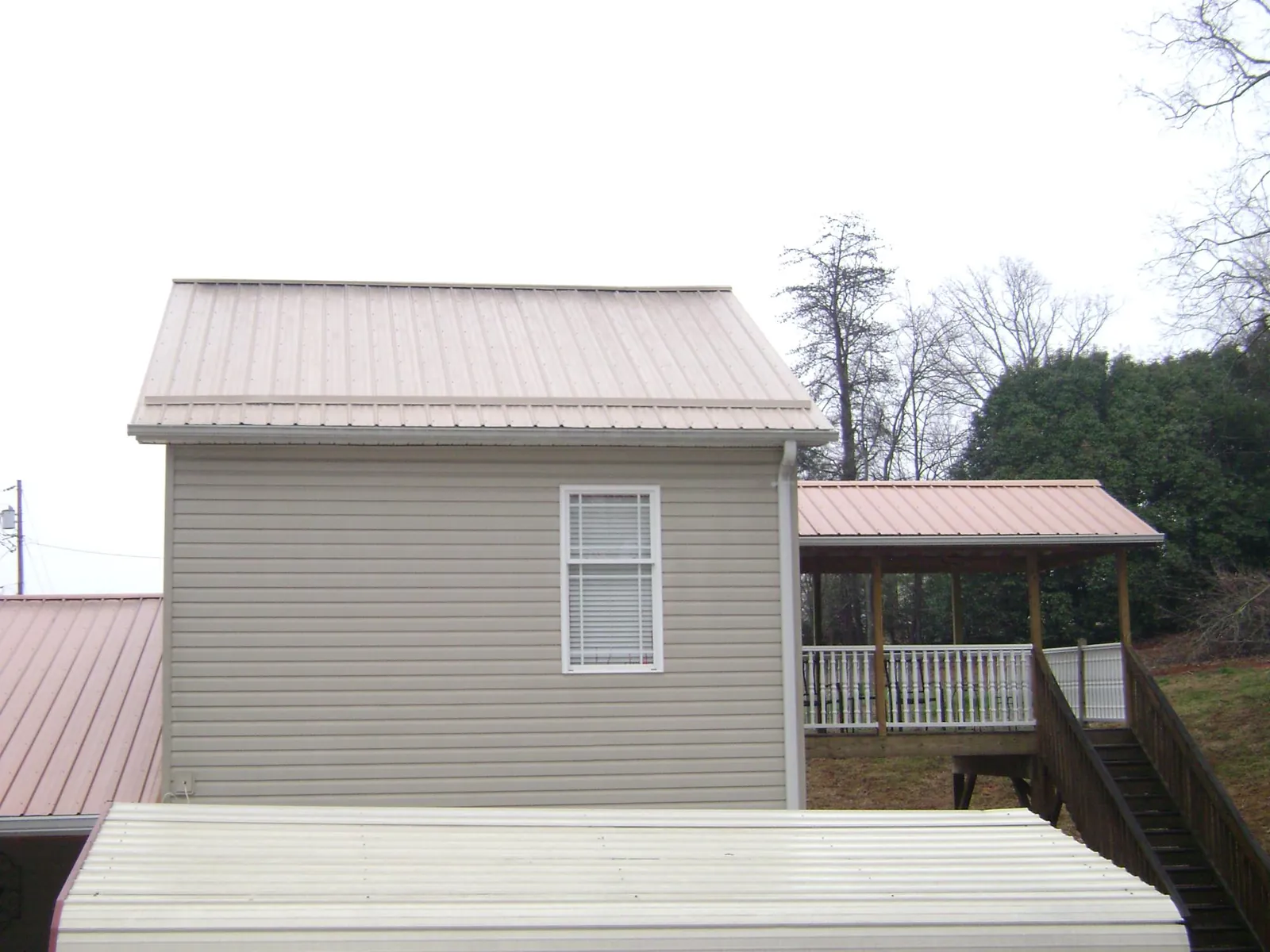 Tan metal roofs on a two story addition and attached porch, from a Roof Replacement job in Glasgow